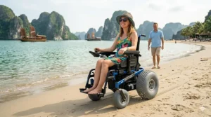 A person smiling while driving an electric beach wheelchair across a sandy shoreline.