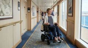 A woman navigating a wide hallway on a cruise ship using a maneuverable travel power wheelchair.