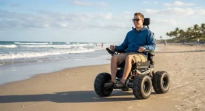 All terrain power wheelchair equipped with wide tires riding along a sandy beach.