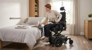 User demonstrating safe lateral transfer from an elevating power wheelchair to a bed.