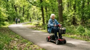 A man enjoying a sunny afternoon on an accessible paved path outdoors in a power wheelchair for MS patients.