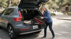 A parent loading a lightweight foldable electric wheelchair for teens into a crossover car trunk